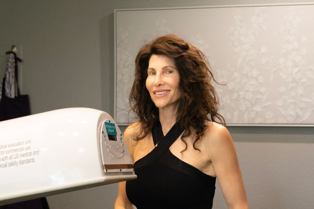 Refined Hair specialist beside the red light therapy unit