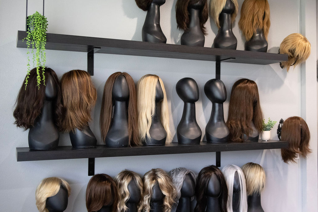 Wall of wigs and toppers on display in the studio