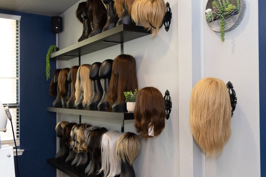 Wigs and toppers displayed on the studio wall
